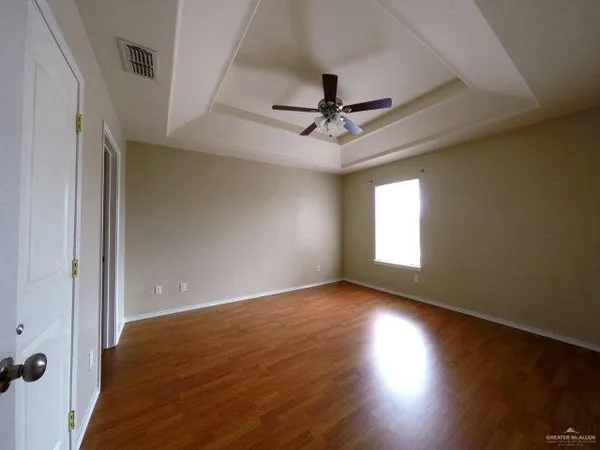 an empty room with wooden floor fan and windows