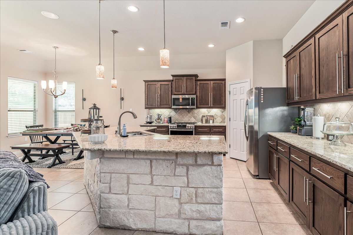137 Navigator Drive Austin, TX 78717 - Photo 8 of 18 a kitchen with stainless steel appliances kitchen island granite countertop a sink a stove a refrigerator and cabinets