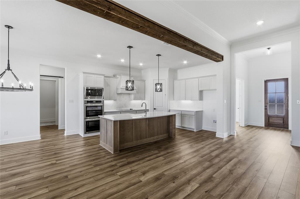 810 Vly Rdg Road Van Alstyne, TX 75495 - Photo 9 of 39 Kitchen with two tone color scheme, an island with sink, dark wood-style floors, stainless steel appliances, and suspended lighting