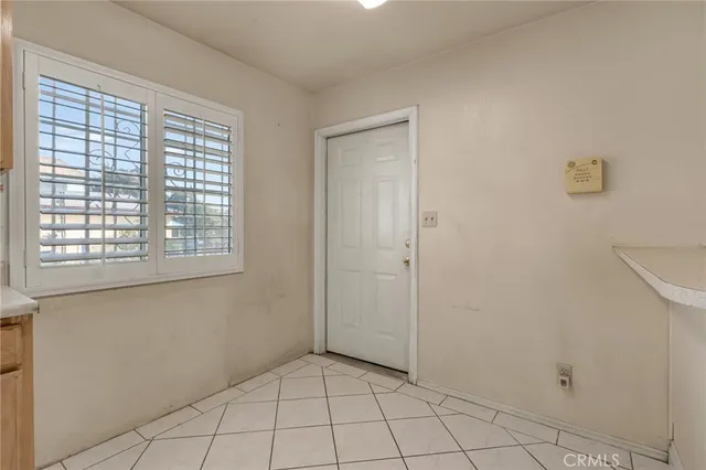 a view of an empty room with window and cabinet area