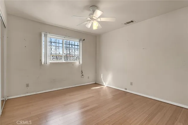 an empty room with wooden floor and a ceiling fan