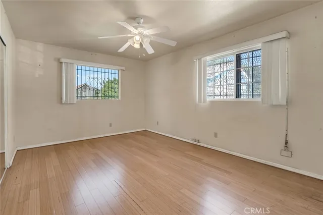 an empty room with wooden floor and a ceiling fan