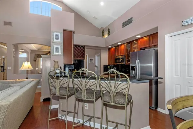 a very nice looking dining room with kitchen island stainless steel appliances furniture a large window and a refrigerator