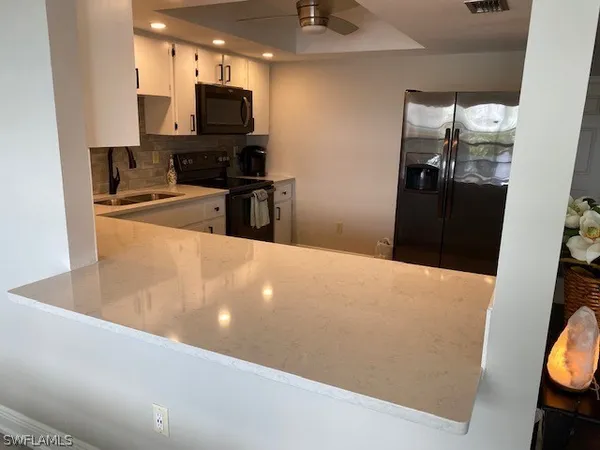 a living room with stainless steel appliances furniture a fireplace and a projector