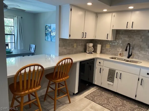a kitchen with a sink white cabinets and appliances