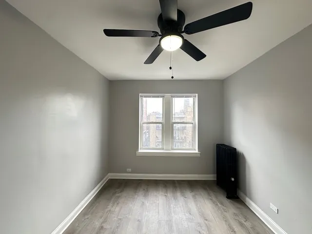 an empty room with wooden floor fan and windows