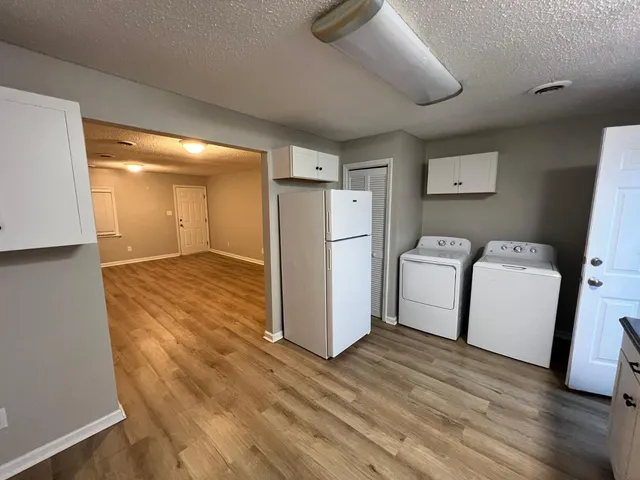 a view of a refrigerator in kitchen and an empty room