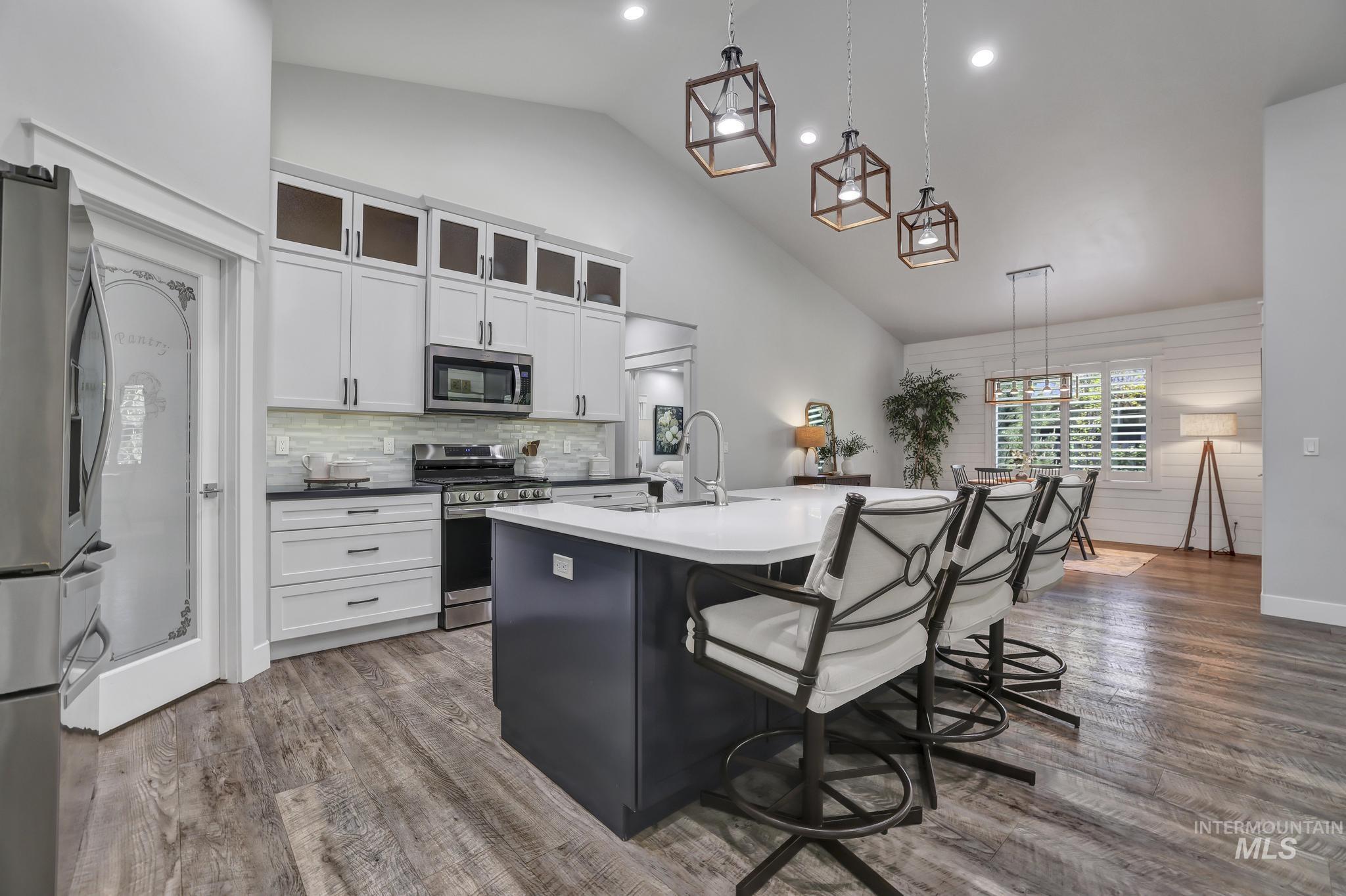 1937 Tamarack Loop Twin Falls, ID 83301 - Photo 13 of 50 Open-concept kitchen featuring vaulted ceilings, wood-finish flooring, a central island with countertop seating, and a full suite of stainless steel appliances