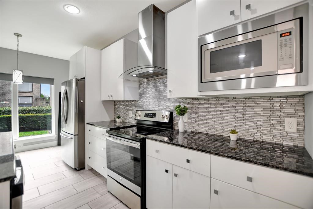20 Evanston Street Houston, TX 77015 - Photo 7 of 31 a kitchen with stainless steel appliances kitchen island granite countertop a stove a microwave and refrigerator