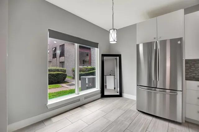 a view of a kitchen with wooden floor a refrigerator and windows