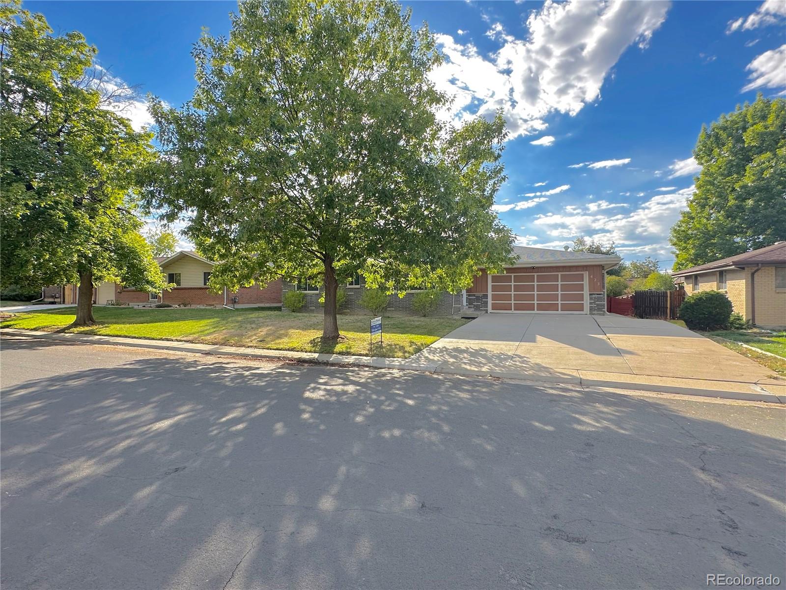 a view of a house with a yard and a large tree