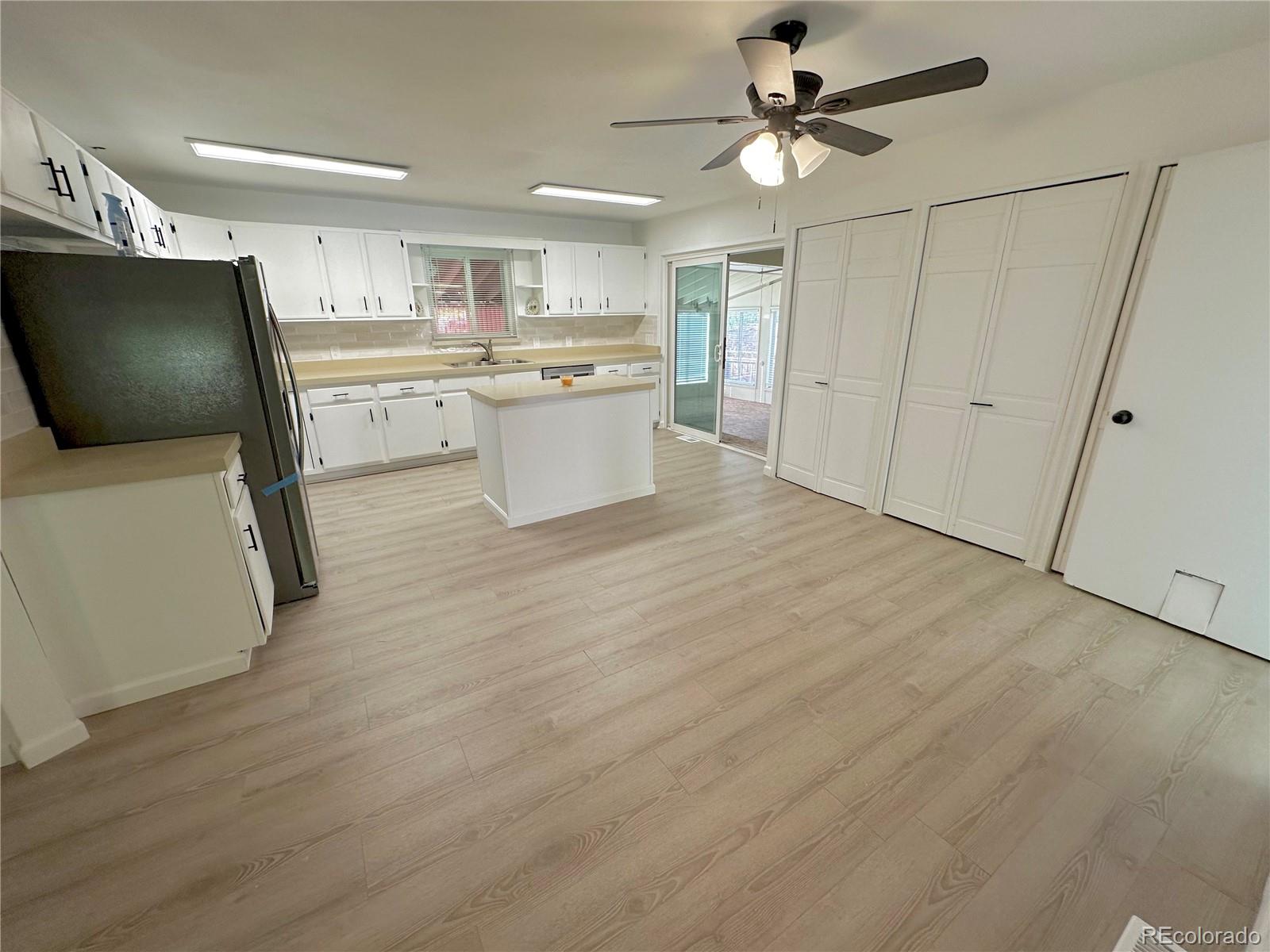 423 Empire Street Aurora, CO 80010 - Photo 5 of 44 a kitchen with stainless steel appliances a refrigerator a sink dishwasher a stove and white cabinets with wooden floor