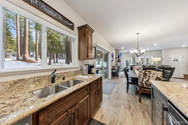 a kitchen with a stove a sink dishwasher and a dining table with wooden floor