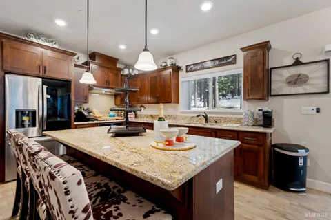 a kitchen with a stove a sink dishwasher and a dining table with wooden floor