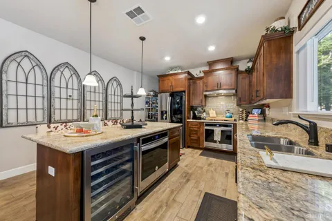 a kitchen with granite countertop a sink a counter space appliances and cabinets