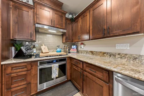 a kitchen with stainless steel appliances granite countertop a refrigerator a stove and a sink