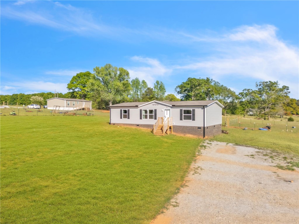 5303 Highway 413 Iva, SC 29655 - Photo 3 of 27 A well-maintained manufactured home sits on a spacious lot under a bright sky.