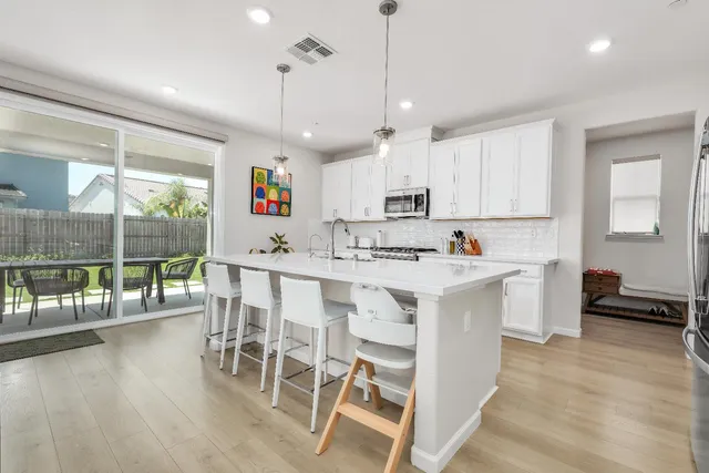 a kitchen with stainless steel appliances kitchen island wooden floors and white cabinets