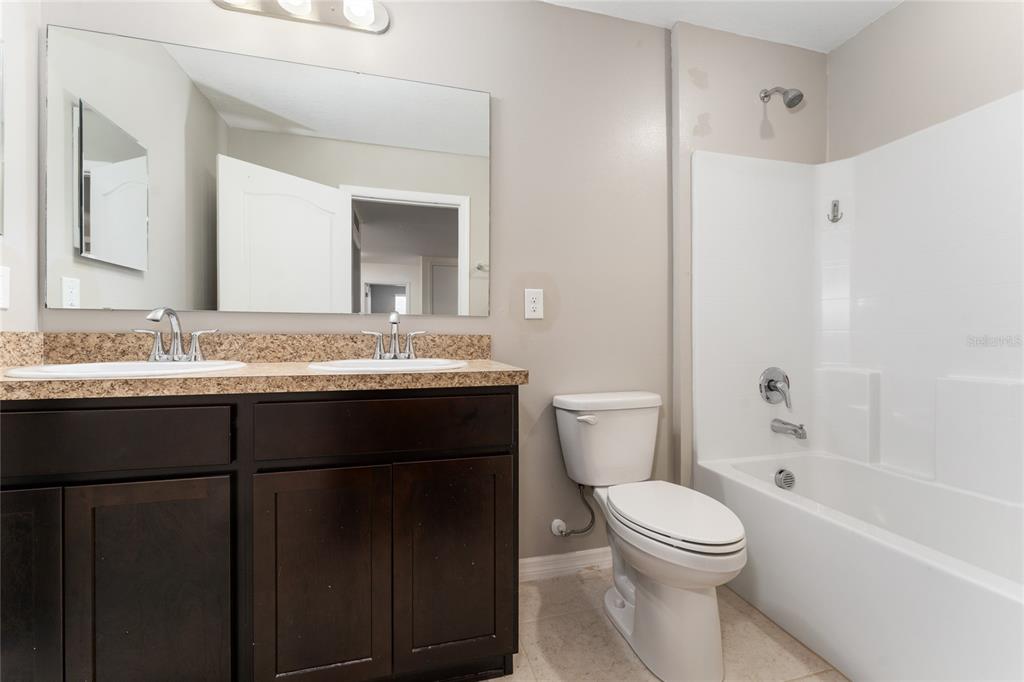 4331 Wayne Road Fruitland Park, FL 34731 - Photo 31 of 46 a bathroom with a granite countertop sink toilet a large mirror a bathtub and shower