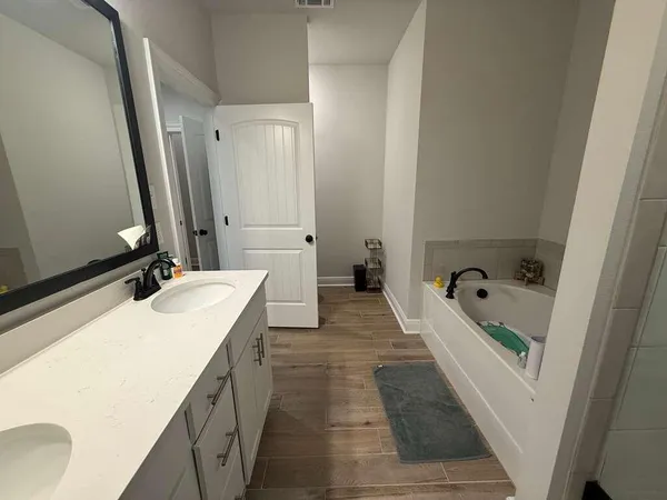a bathroom with a double vanity sink and mirror with bathtub