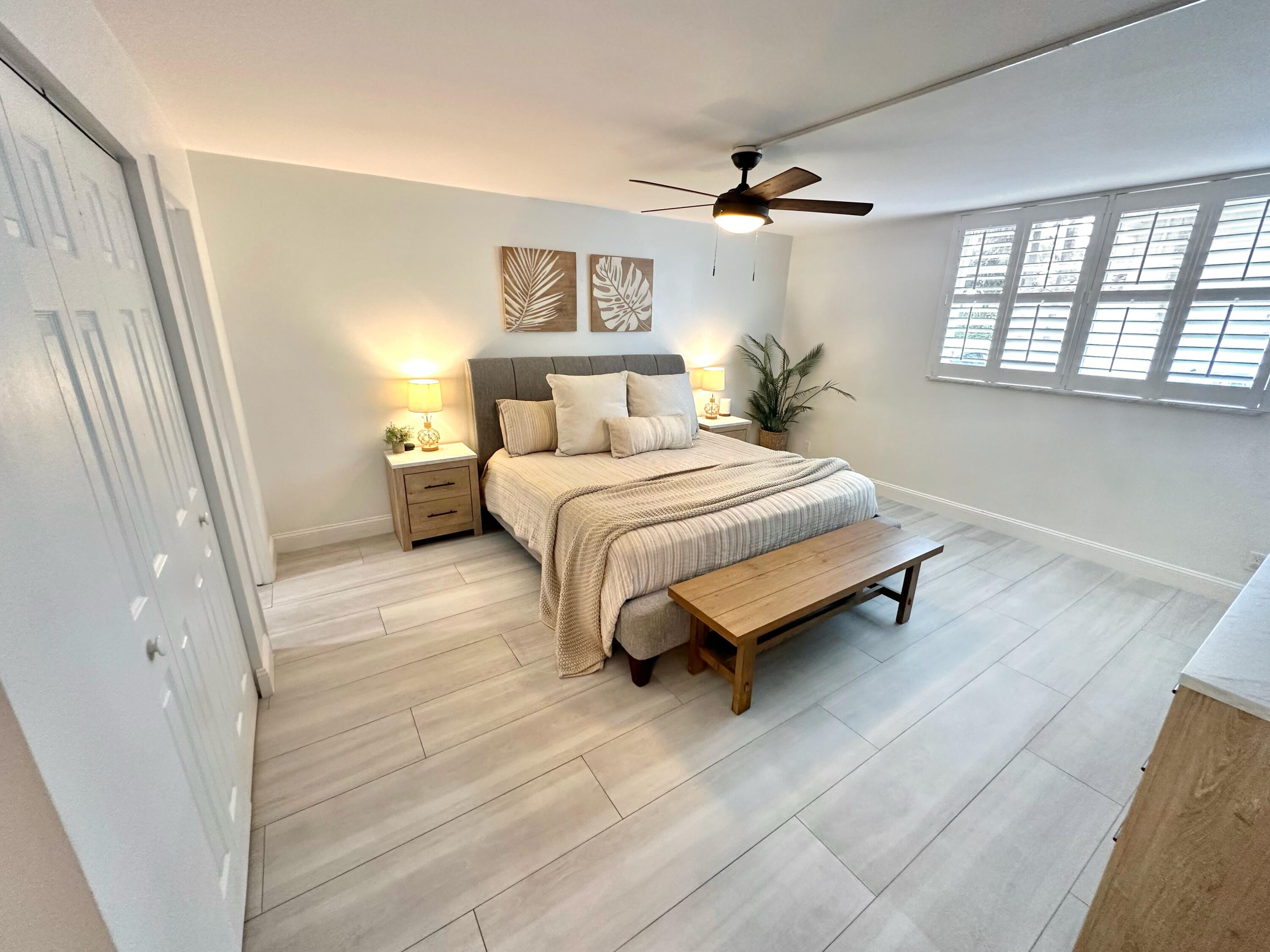 630 Ocean Drive, Unit 105 Juno Beach, FL 33408 - Photo 13 of 37 a spacious bedroom with a bed lamp on table and a window
