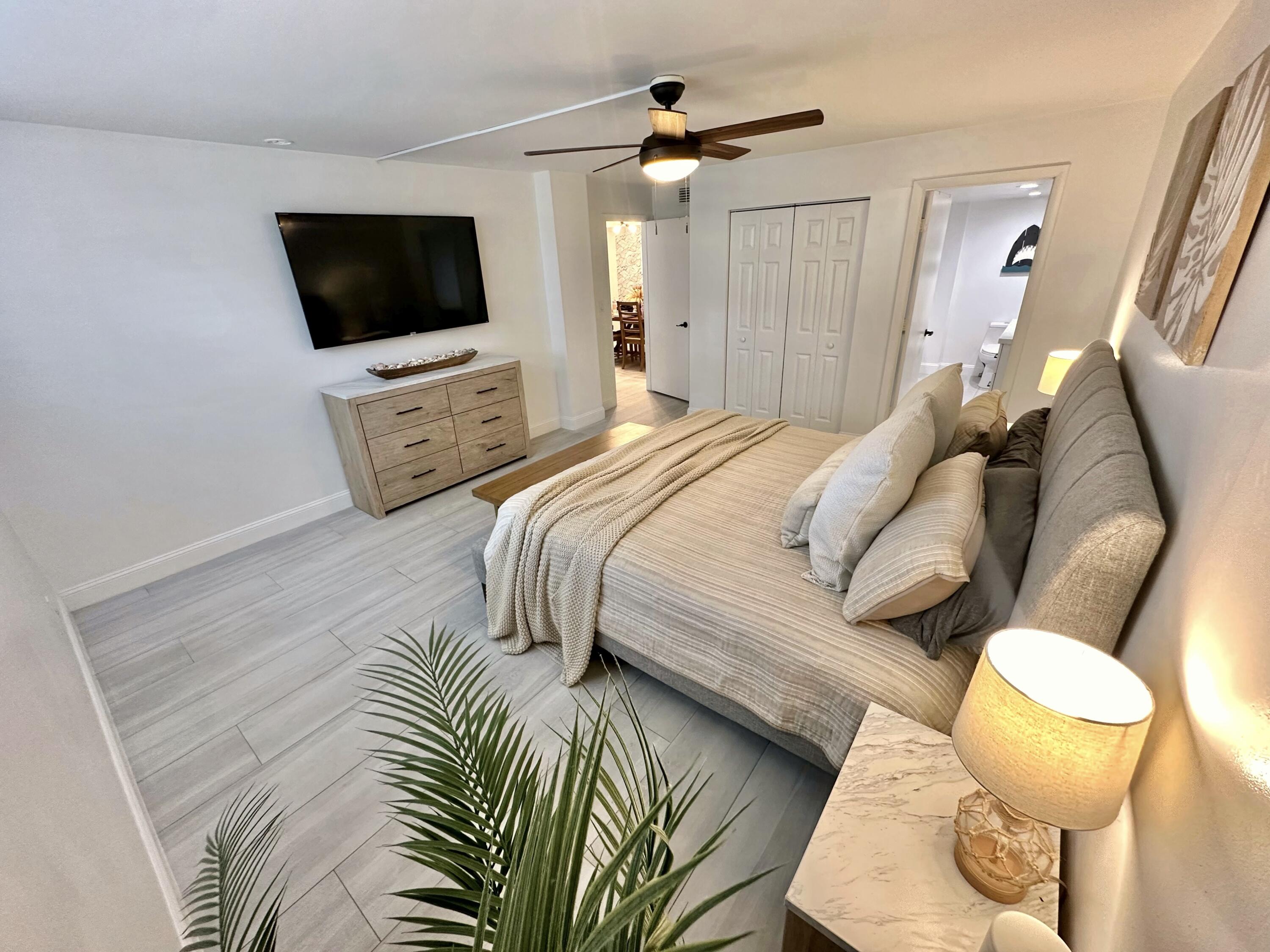 630 Ocean Drive, Unit 105 Juno Beach, FL 33408 - Photo 14 of 37 a bedroom with a bed and a flat screen tv