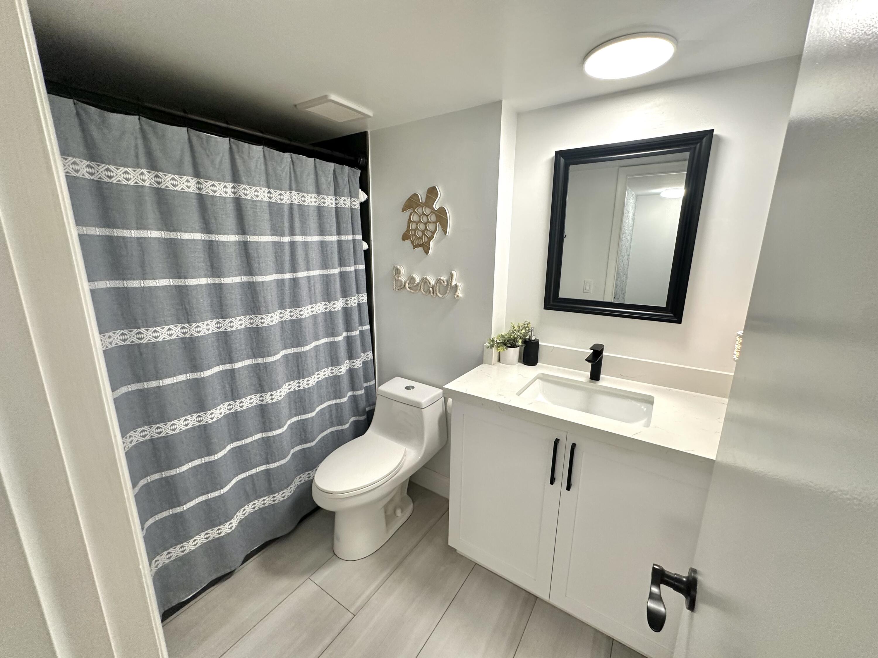 630 Ocean Drive, Unit 105 Juno Beach, FL 33408 - Photo 23 of 37 a bathroom with a sink toilet and shower