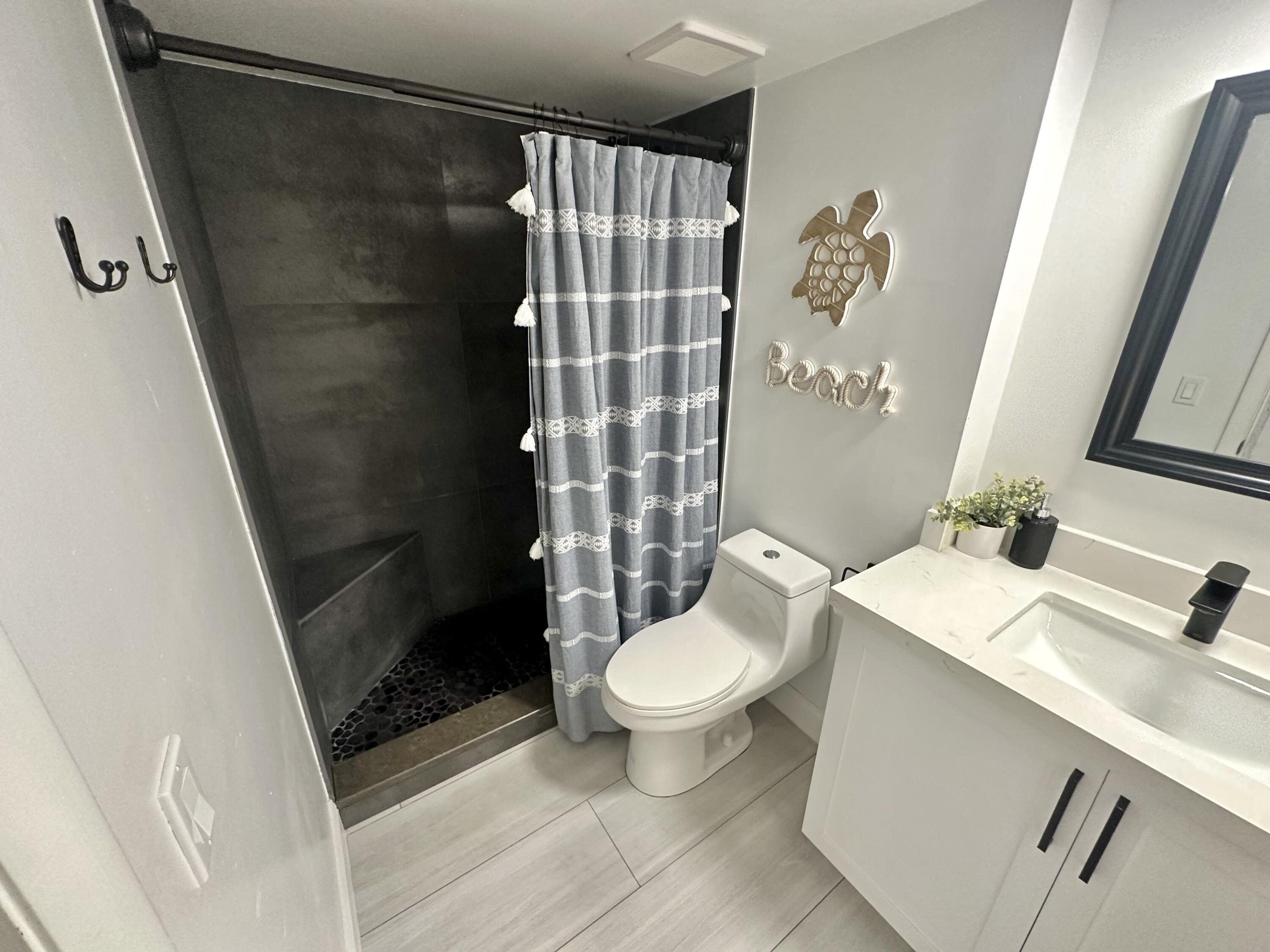 630 Ocean Drive, Unit 105 Juno Beach, FL 33408 - Photo 24 of 37 a bathroom with a sink a toilet a shower and a mirror