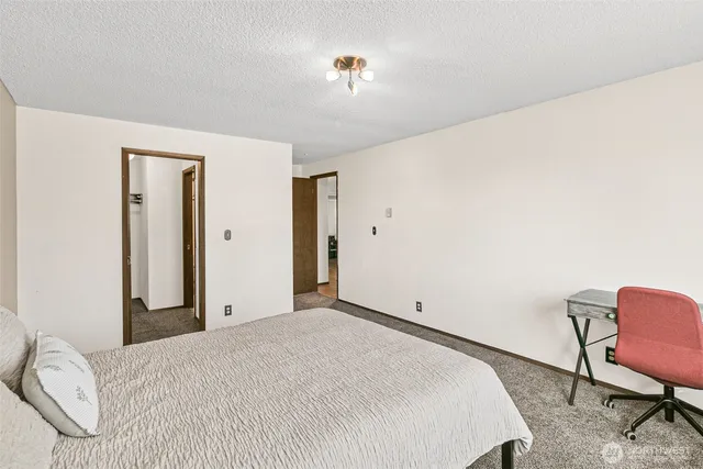 a bedroom with a bed a chair and potted plant