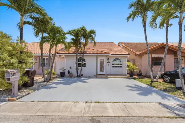 a front view of a house with a yard and palm tree