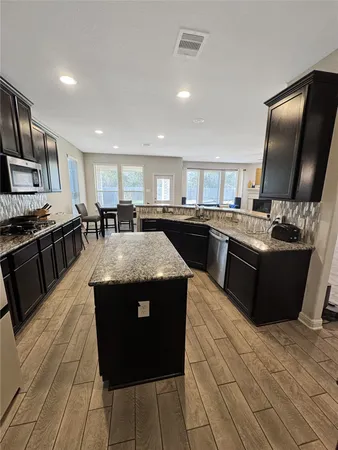 a kitchen with stainless steel appliances granite countertop a stove a sink and a microwave