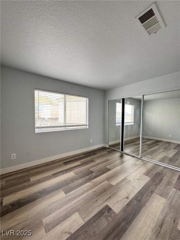 678 Anne Lane, Unit 678 Henderson, NV 89015 - Photo 11 of 14 Unfurnished bedroom with a closet, a textured ceiling, and wood finished floors