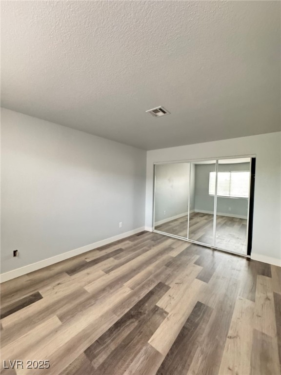 678 Anne Lane, Unit 678 Henderson, NV 89015 - Photo 14 of 14 Unfurnished bedroom with a closet, light wood-style floors, and a textured ceiling