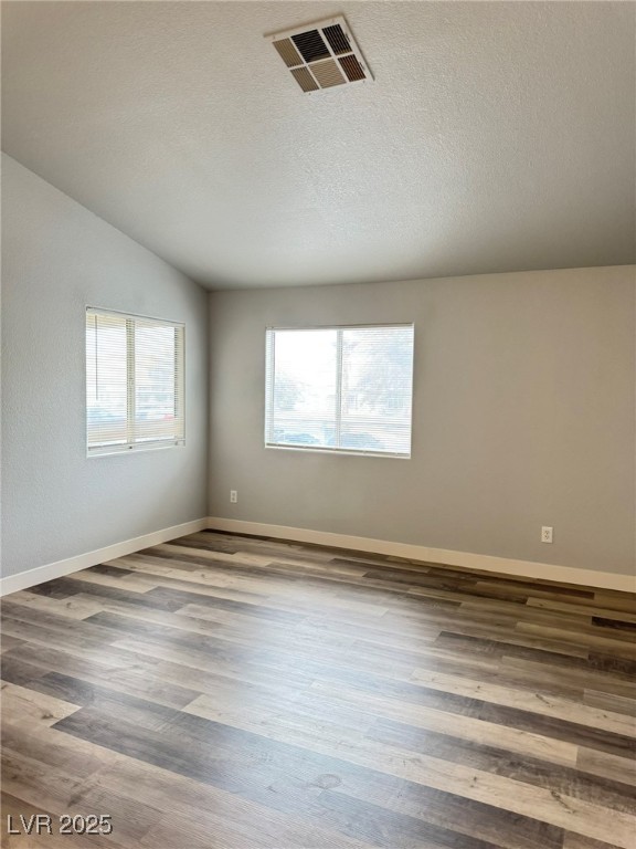 678 Anne Lane, Unit 678 Henderson, NV 89015 - Photo 4 of 14 Spare room with plenty of natural light, wood finished floors, and a textured ceiling