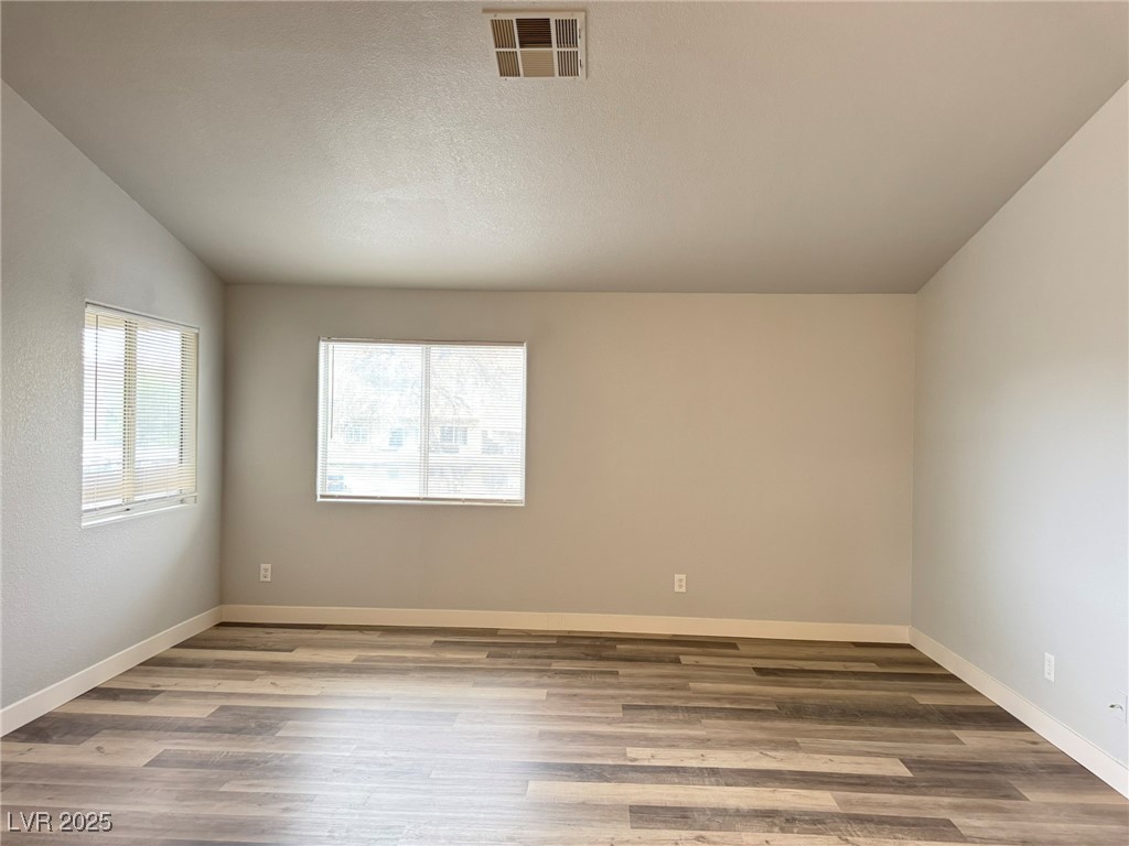 678 Anne Lane, Unit 678 Henderson, NV 89015 - Photo 5 of 14 Spare room with light wood-style flooring, vaulted ceiling, and a textured ceiling