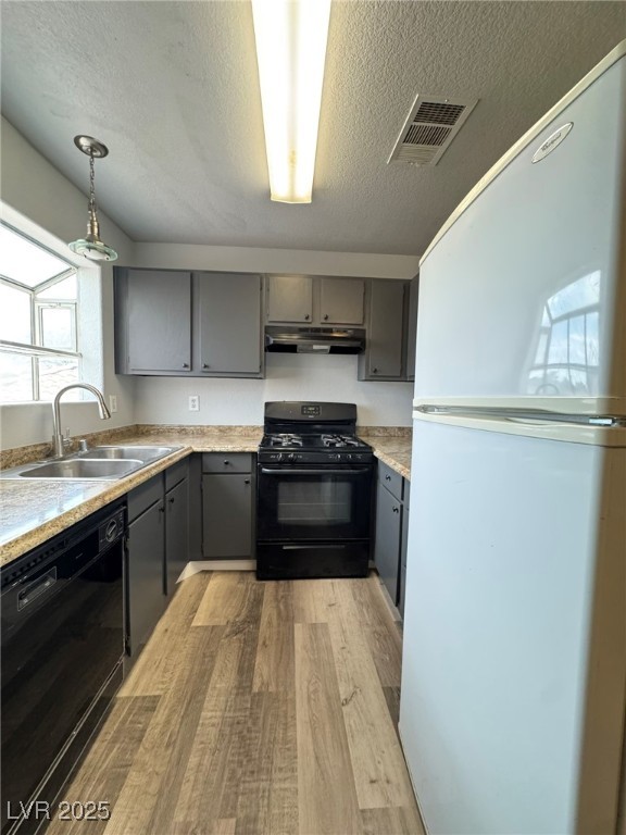 678 Anne Lane, Unit 678 Henderson, NV 89015 - Photo 8 of 14 Kitchen featuring black appliances, light wood-style flooring, gray cabinets, a textured ceiling, and light countertops