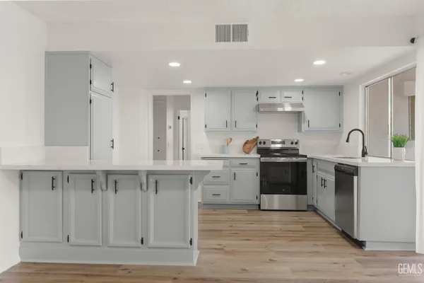 a view of an empty room with wooden floor and a fireplace