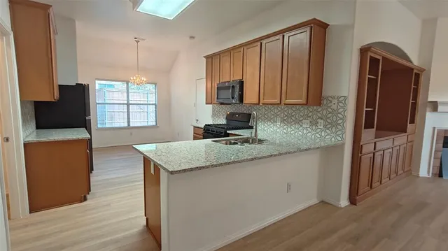 a kitchen with stainless steel appliances granite countertop a sink a microwave a refrigerator and grey cabinets