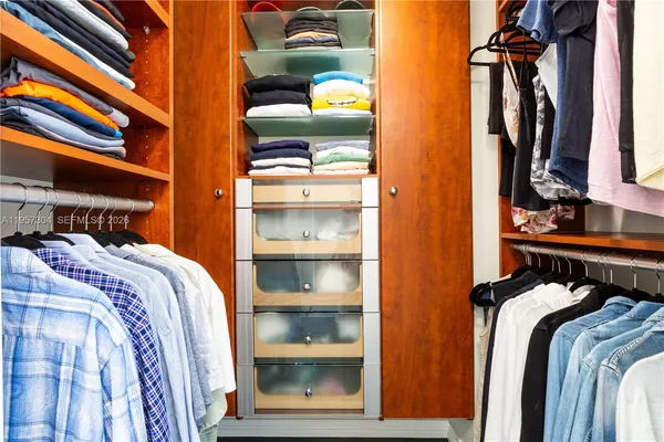 a view of walk in closet with clothes and shoes