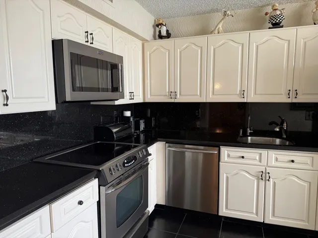 a kitchen with stainless steel appliances granite countertop white cabinets sink and dishwasher