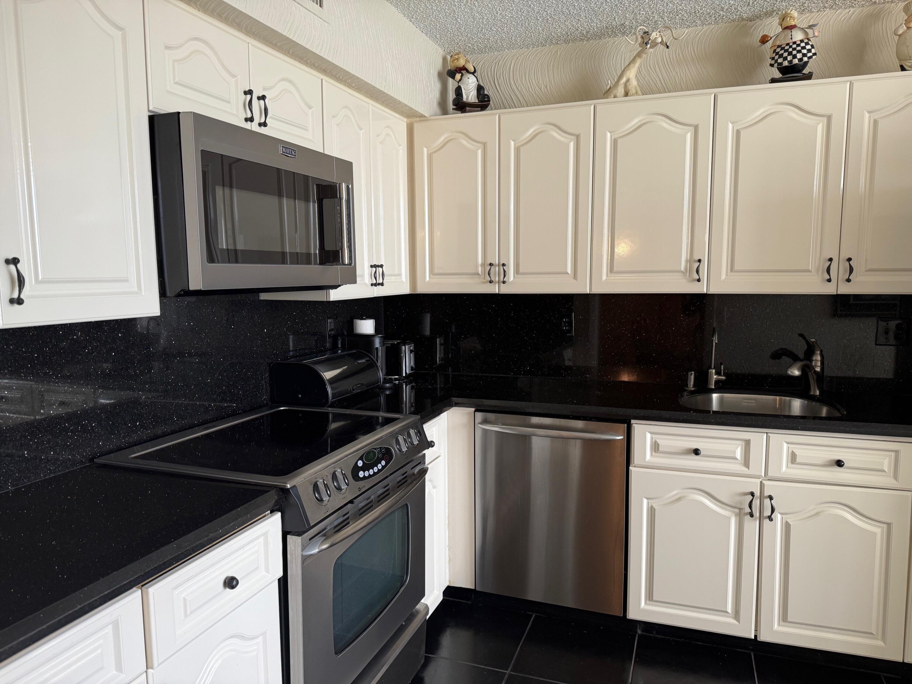 7564 Regency Lake Drive, Unit 702 Boca Raton, FL 33433 - Photo 3 of 40 a kitchen with stainless steel appliances granite countertop white cabinets sink and dishwasher