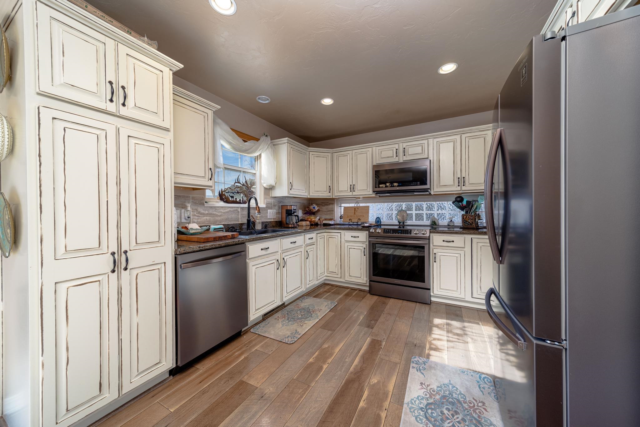 1124 West Addington Lane Fruita, CO 81521 - Photo 3 of 25 a kitchen with granite countertop white cabinets and stainless steel appliances