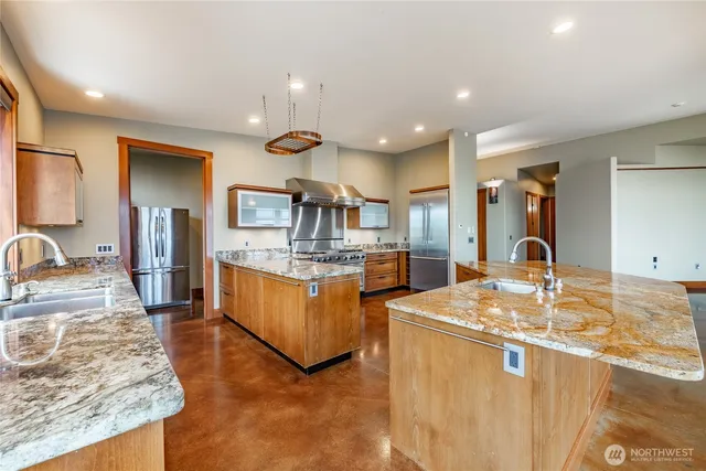 a large kitchen with kitchen island a large counter top stainless steel appliances and cabinets