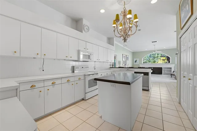 a kitchen with white cabinets appliances and chandelier