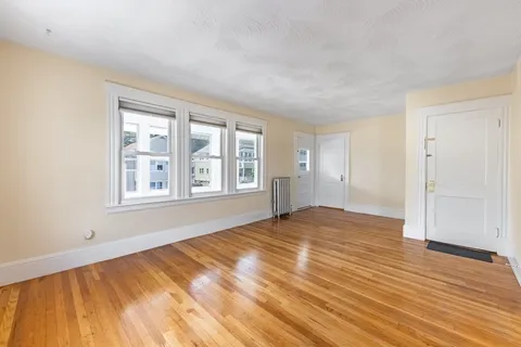 a view of empty room with wooden floor and windows