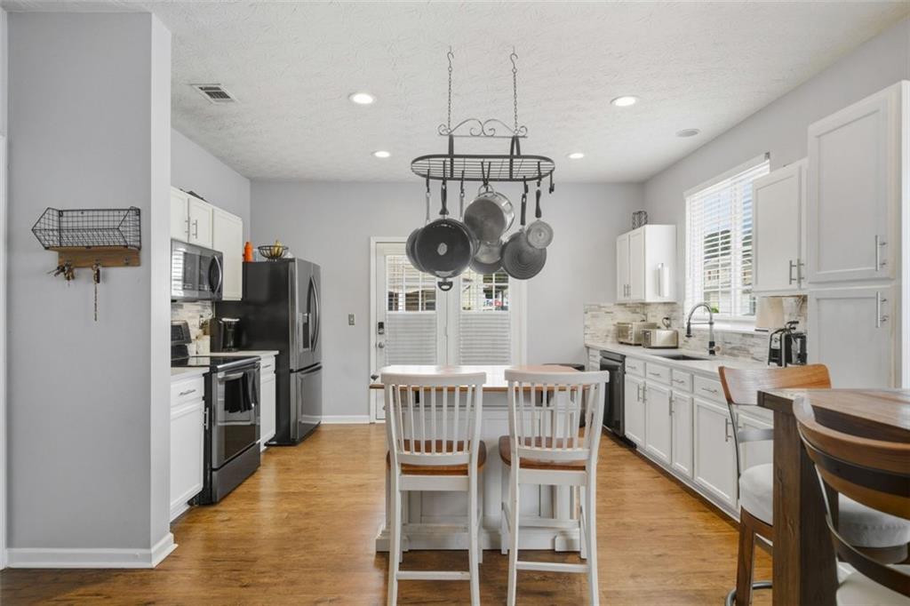 3635 Roseman Landing Cumming, GA 30040 - Photo 4 of 31 a kitchen with stainless steel appliances a dining table chairs stove and refrigerator