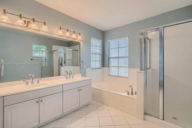 a bathroom with a double vanity sink mirror and bathtub