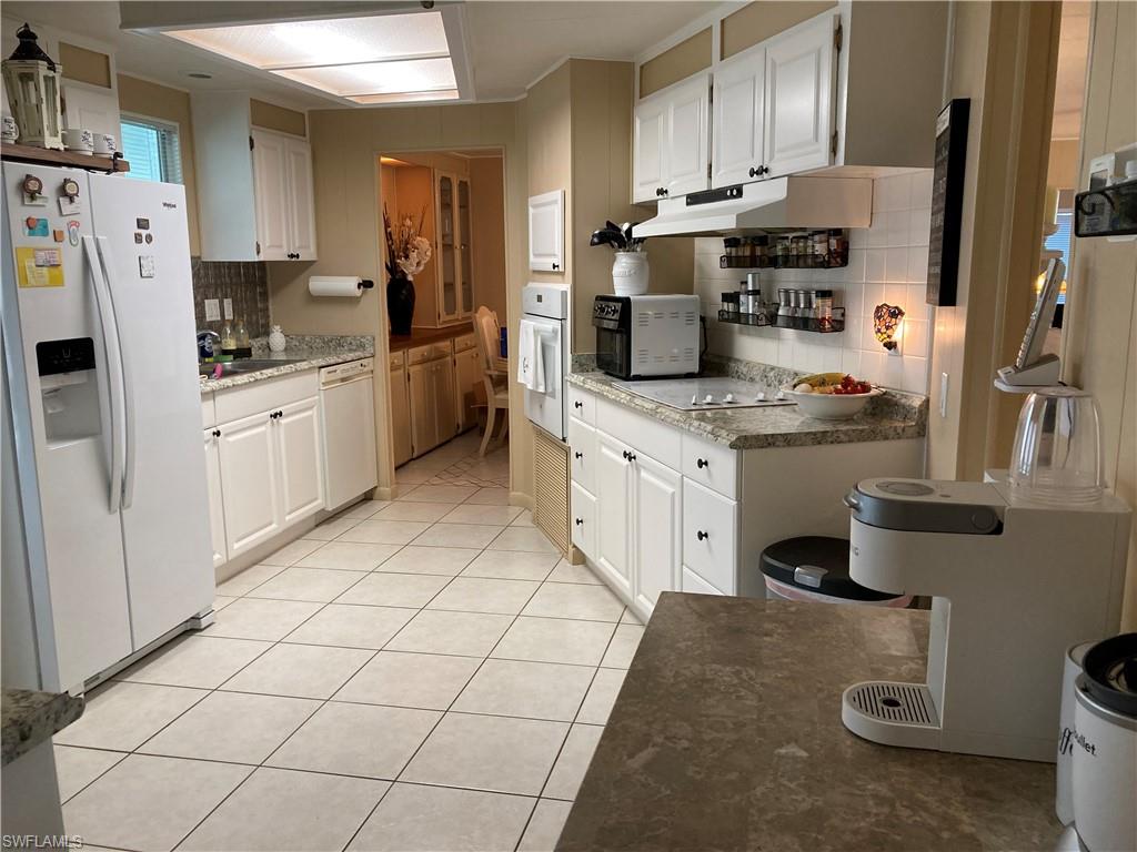 32 Lemans Drive Naples, FL 34112 - Photo 13 of 49 a kitchen with stainless steel appliances kitchen island granite countertop a refrigerator a stove a sink dishwasher and white cabinets with wooden floor