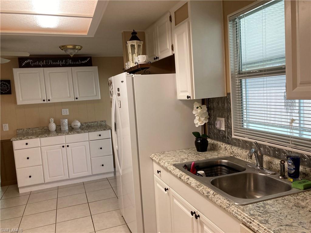 32 Lemans Drive Naples, FL 34112 - Photo 14 of 49 a kitchen with granite countertop a sink stove and refrigerator