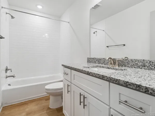 a bathroom with a granite countertop sink a toilet and bathtub